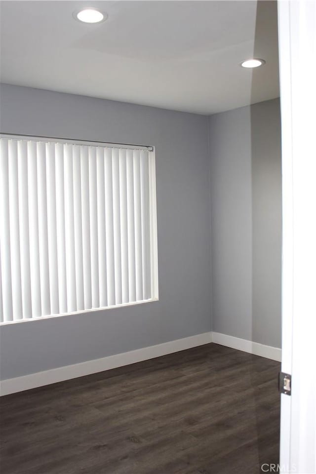 spare room featuring dark wood-type flooring, recessed lighting, and baseboards