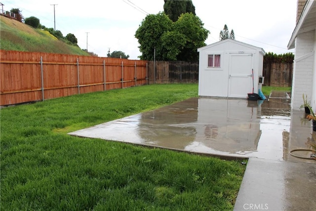 view of yard with an outbuilding, a storage unit, a fenced backyard, and a patio area