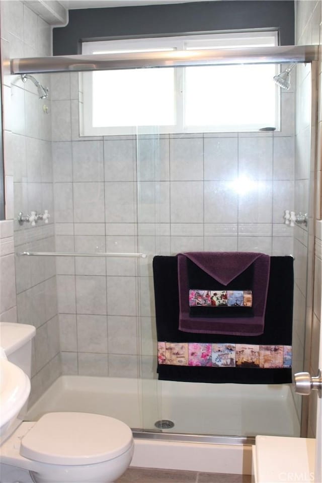 bathroom featuring toilet and a stall shower