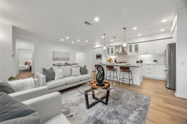 living room featuring light wood finished floors, recessed lighting, visible vents, and baseboards