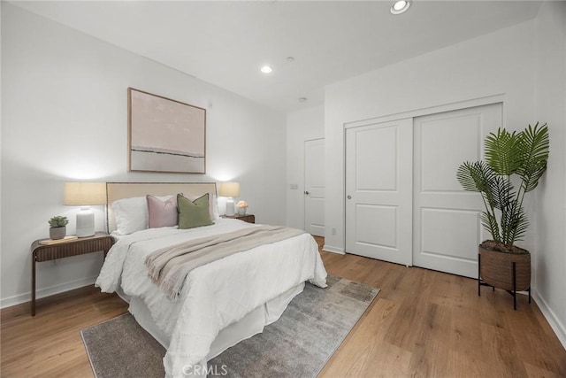 bedroom with baseboards, light wood-type flooring, a closet, and recessed lighting