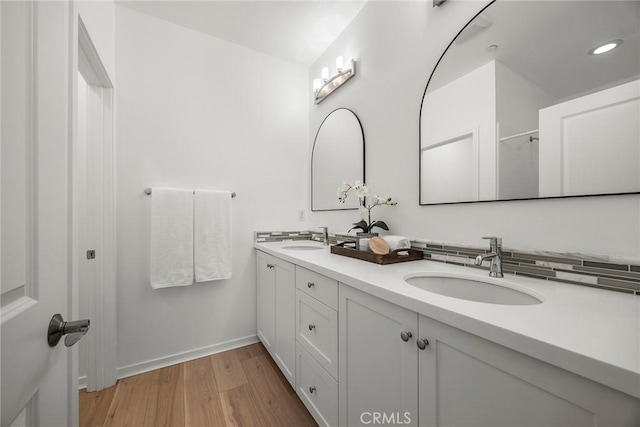 full bath featuring double vanity, wood finished floors, baseboards, and a sink
