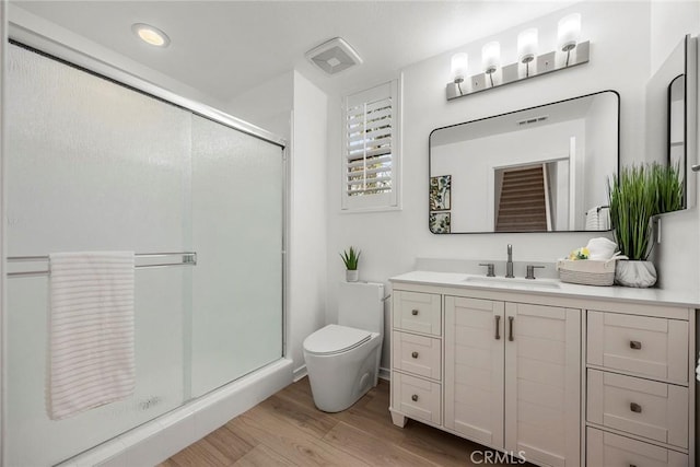 bathroom featuring recessed lighting, a shower stall, vanity, toilet, and wood finished floors