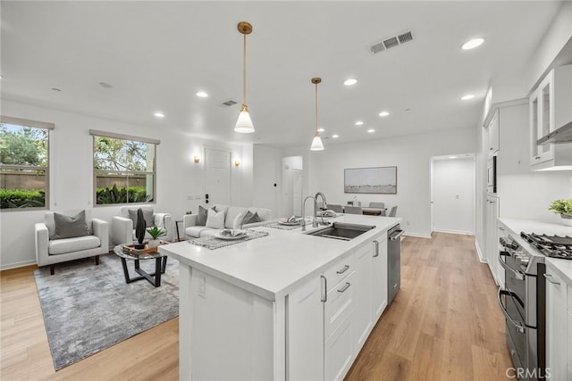 kitchen featuring a sink, open floor plan, stainless steel appliances, light countertops, and white cabinetry
