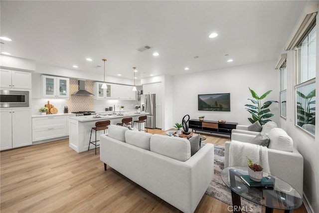 living area with recessed lighting, light wood-style floors, and visible vents