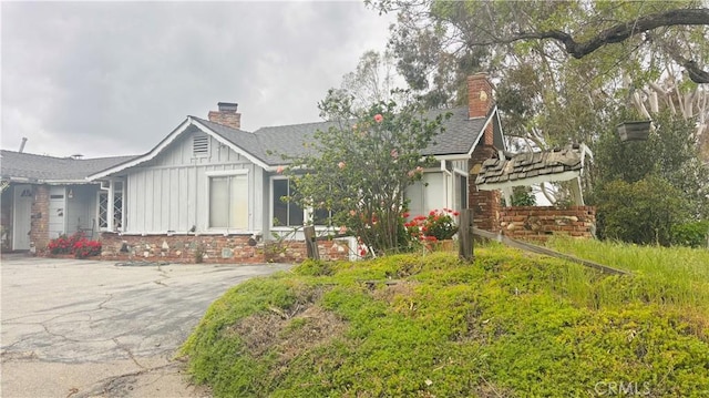 single story home featuring a chimney, roof with shingles, and board and batten siding