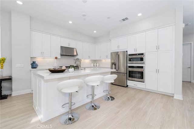 102 Pattern, Irvine, CA 92618 - kitchen with under cabinet range hood, stainless steel appliances, light countertops, white cabinetry, and visible vents