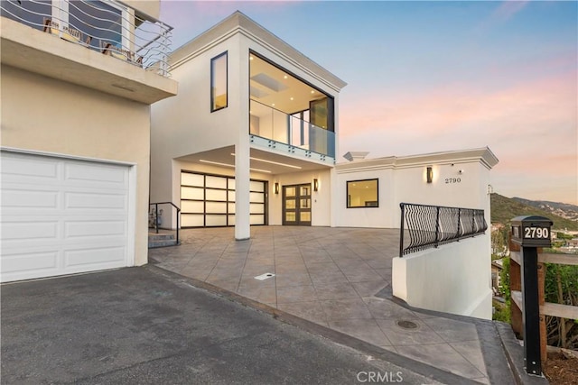 exterior space with driveway, stucco siding, an attached garage, and a balcony