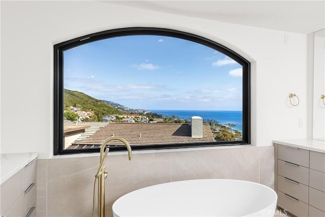 bathroom featuring a soaking tub, vanity, and tile walls