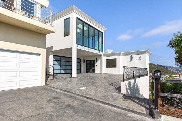 view of front of house with stucco siding, a balcony, and a garage