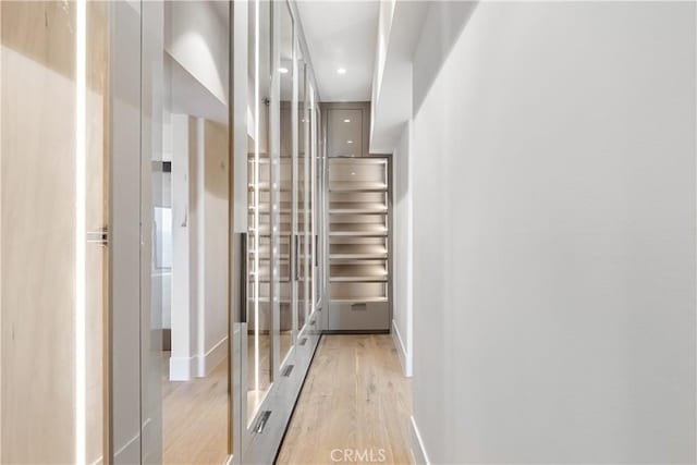 corridor featuring light wood finished floors, recessed lighting, and baseboards