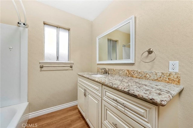 14306 Boxtree St, Lake Hughes, CA 93532 - bathroom featuring wood finished floors, vanity, baseboards, a bathtub, and walk in shower