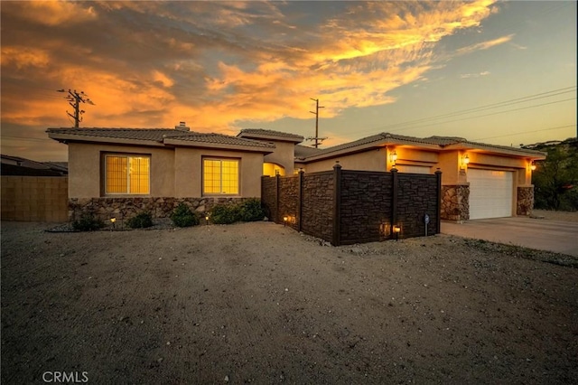 7625 Pinon Dr, Yucca Valley, CA 92284 - view of front of house with stone siding, an attached garage, a tile roof, stucco siding, and concrete driveway