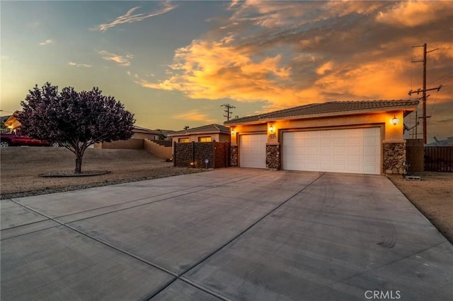 7625 Pinon Dr, Yucca Valley, CA 92284 - view of front of property featuring stone siding, driveway, a tiled roof, an attached garage, and stucco siding