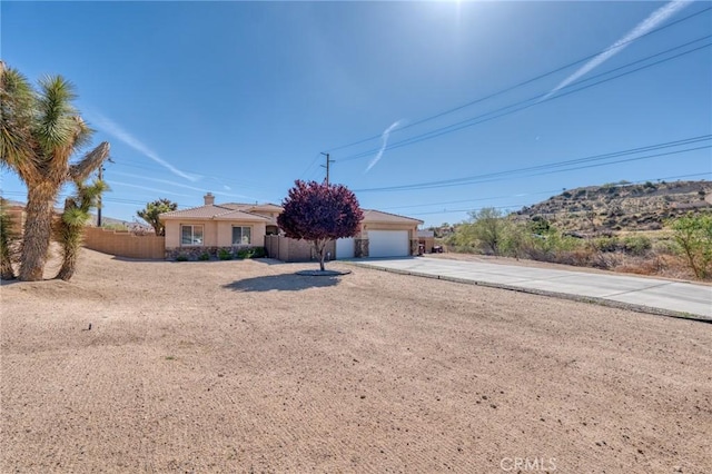 7625 Pinon Dr, Yucca Valley, CA 92284 - view of front facade with driveway, stucco siding, a chimney, and a garage