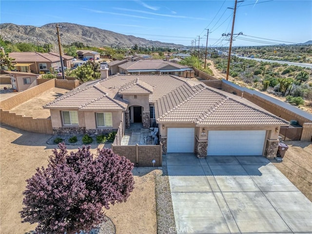 7625 Pinon Dr, Yucca Valley, CA 92284 - mediterranean / spanish home with stone siding, stucco siding, a garage, concrete driveway, and a mountain view