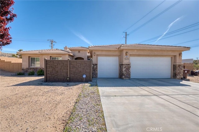 7625 Pinon Dr, Yucca Valley, CA 92284 - view of front of home featuring stucco siding, concrete driveway, a garage, stone siding, and a tiled roof