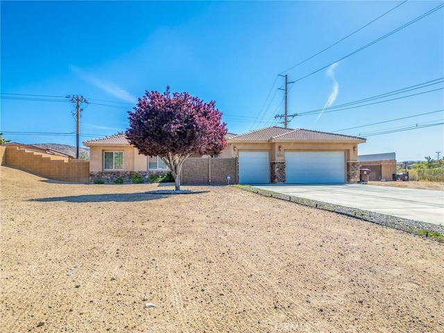 7625 Pinon Dr, Yucca Valley, CA 92284 - view of front of house featuring stucco siding, a tiled roof, stone siding, driveway, and a garage