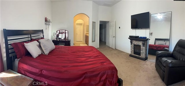 7625 Pinon Dr, Yucca Valley, CA 92284 - carpeted bedroom featuring arched walkways, a stone fireplace, and ensuite bath