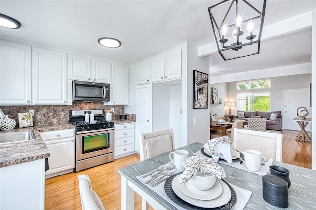 22911 Via Santiago, Mission Viejo, CA 92691 - kitchen with a sink, a chandelier, stainless steel appliances, decorative backsplash, and white cabinets