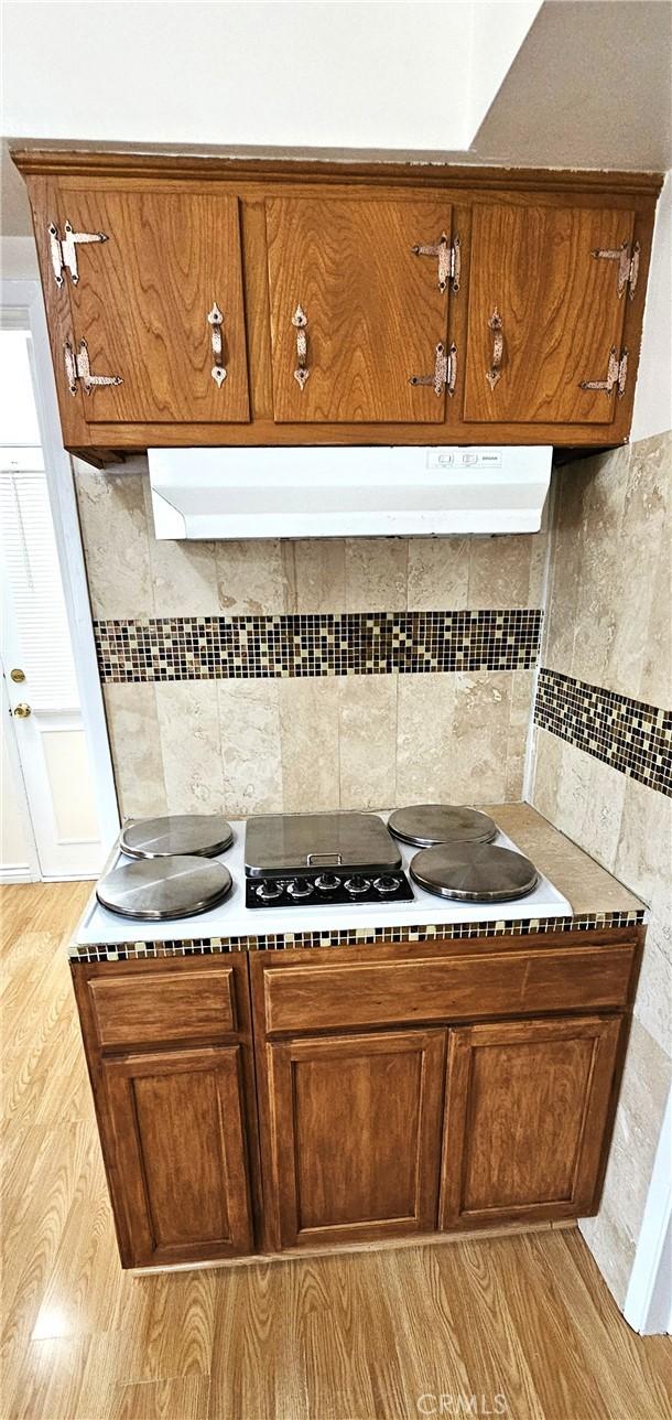 1060 Newhill St, Glendora, CA 91741 - kitchen featuring brown cabinets, under cabinet range hood, and tasteful backsplash