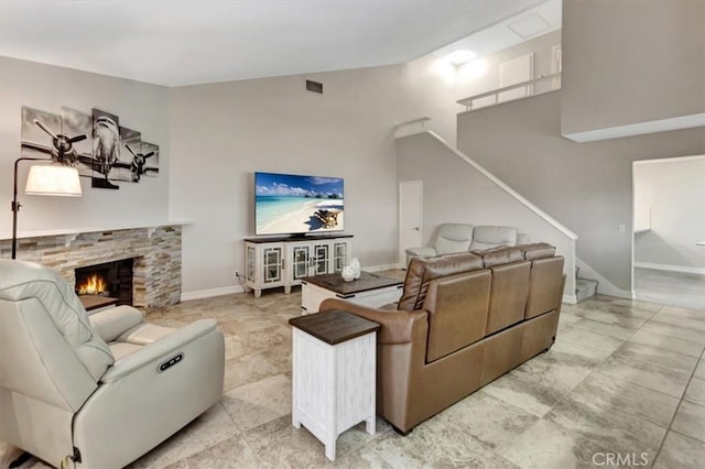living area with light tile patterned floors, baseboards, stairs, and a fireplace