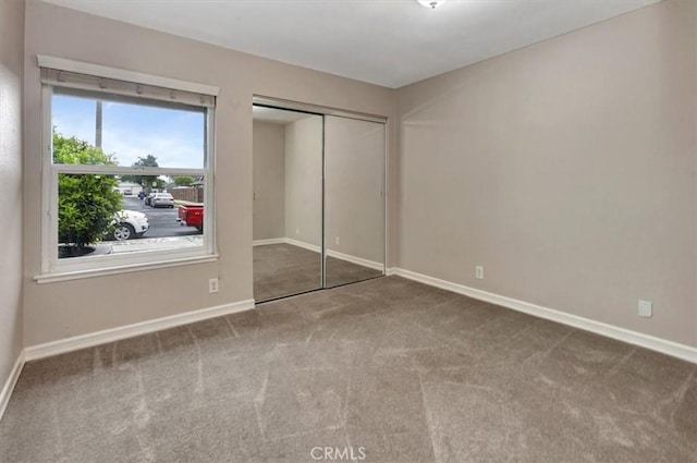 unfurnished bedroom featuring baseboards, carpet floors, and a closet