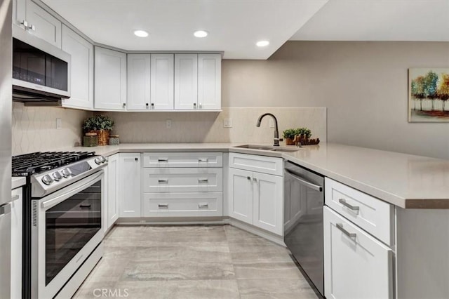 kitchen featuring a peninsula, stainless steel dishwasher, a sink, range with gas cooktop, and white microwave