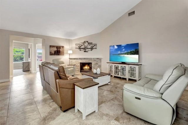 living room featuring baseboards, vaulted ceiling, visible vents, and a fireplace