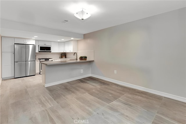 kitchen featuring stainless steel appliances, visible vents, baseboards, a peninsula, and white cabinetry