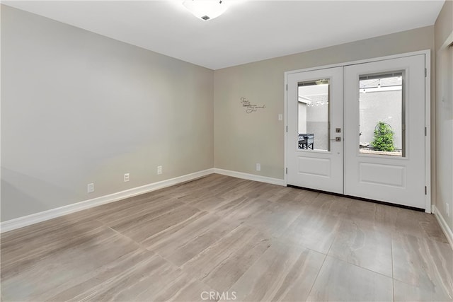 foyer entrance with baseboards, french doors, and light wood-style floors