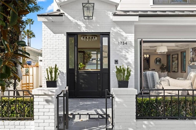 doorway to property with brick siding, fence, and a porch