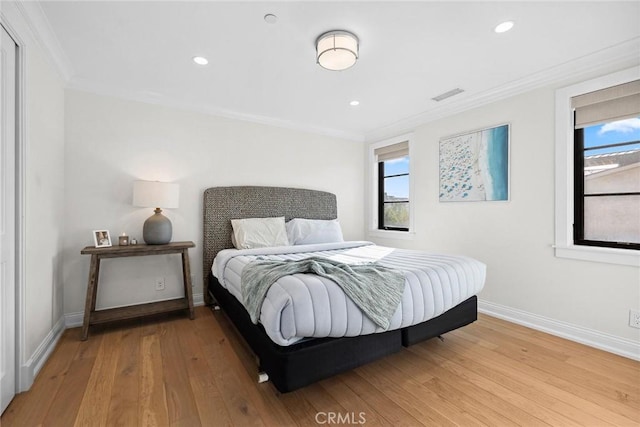 bedroom with baseboards, ornamental molding, wood finished floors, and visible vents