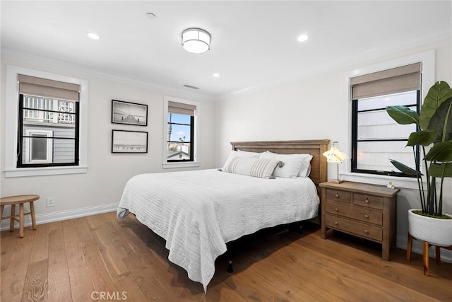 bedroom with recessed lighting, wood finished floors, crown molding, and baseboards
