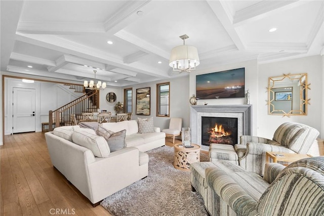 living room with wood-type flooring, coffered ceiling, a notable chandelier, and beamed ceiling