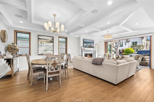 living room featuring a notable chandelier, a glass covered fireplace, and light wood-type flooring