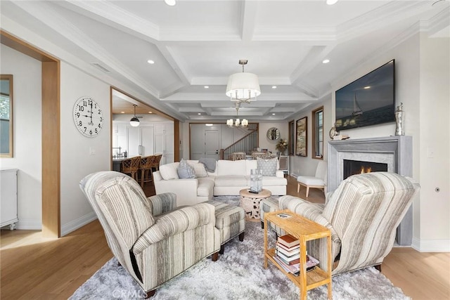 living area featuring a chandelier, a warm lit fireplace, light wood-style floors, and baseboards