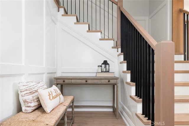 stairs with a decorative wall and wood finished floors