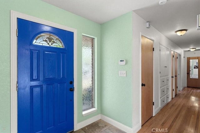 foyer entrance featuring a textured wall, wood finished floors, and baseboards