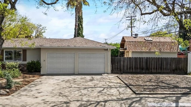 garage with concrete driveway and fence