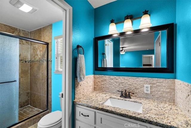 bathroom featuring a shower stall, toilet, and vanity