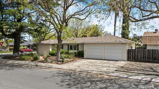 ranch-style house featuring a garage, driveway, stucco siding, and fence