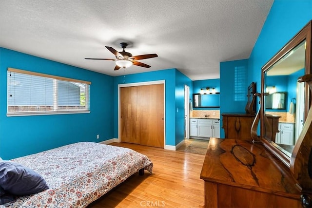 bedroom featuring a closet, a textured ceiling, light wood finished floors, and baseboards