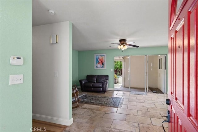 entrance foyer with stone tile floors, baseboards, and ceiling fan