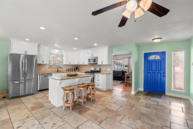 kitchen with stone tile floors, stainless steel appliances, a sink, and tasteful backsplash