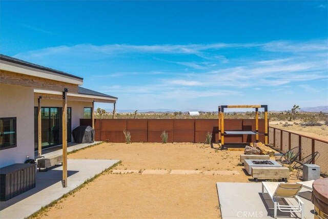 3170 Wesley Rd, Joshua Tree, CA 92252 - fenced backyard featuring a fire pit, a mountain view, and a patio