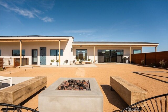 3170 Wesley Rd, Joshua Tree, CA 92252 - back of property featuring an outdoor fire pit, stucco siding, and a patio area