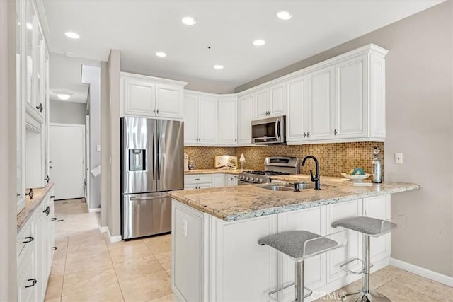 9 Gema, San Clemente, CA 92672 - kitchen featuring appliances with stainless steel finishes, a peninsula, a sink, baseboards, and light stone countertops