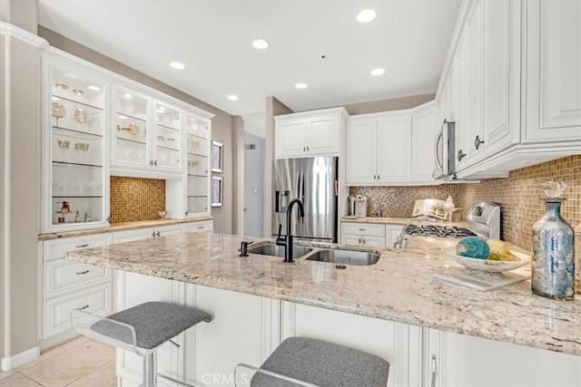 9 Gema, San Clemente, CA 92672 - kitchen featuring appliances with stainless steel finishes, a sink, a peninsula, light stone counters, and a kitchen breakfast bar