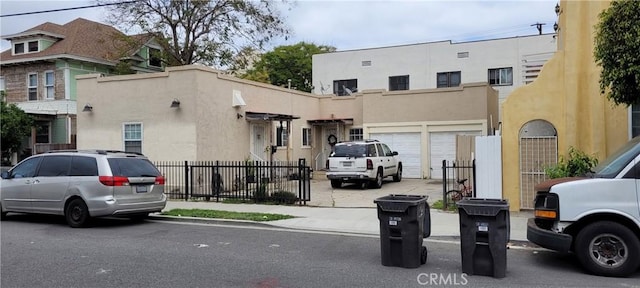 view of front of home featuring an attached garage, driveway, stucco siding, and fence